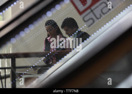 Two business executives working on a laptop viewed through an escalator Stock Photo