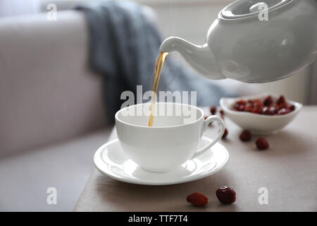 Pouring rose hip tea into cup, home atmosphere Stock Photo