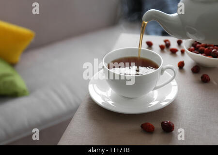 Pouring rose hip tea into cup, home atmosphere Stock Photo