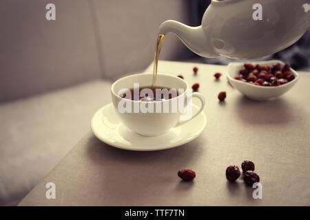 Pouring rose hip tea into cup, home atmosphere Stock Photo