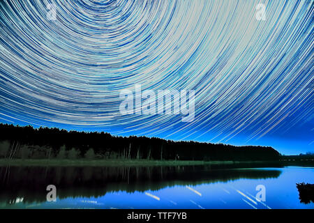 Wonderful beautiful night sky star trail over the river and forest in transparent april night Stock Photo