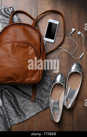 Brown leather backpack with female items on wooden surface, top view Stock Photo