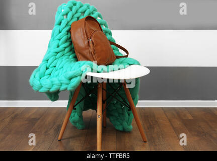 Brown leather backpack with knitted plaid on chair indoors Stock Photo