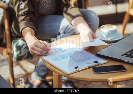 Low section of businesswoman writing on papers in cafe Stock Photo