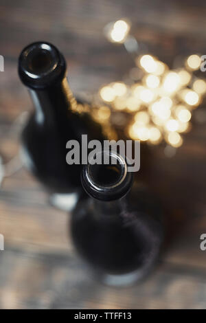 High angle view of champagne bottles with illuminated Christmas lights on wooden table Stock Photo