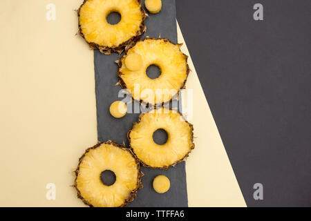 Raw pineapple slices are placed on a black background with yellow Stock Photo