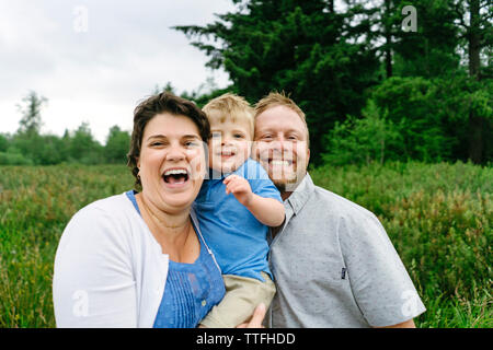 Straight on closeup portrait of a family of three smiling and laughing Stock Photo