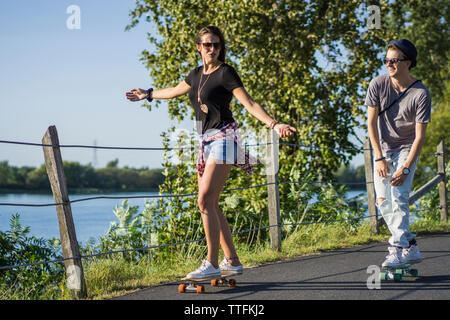 Couple cruising down bike path together on skateboard cruiser bo Stock Photo
