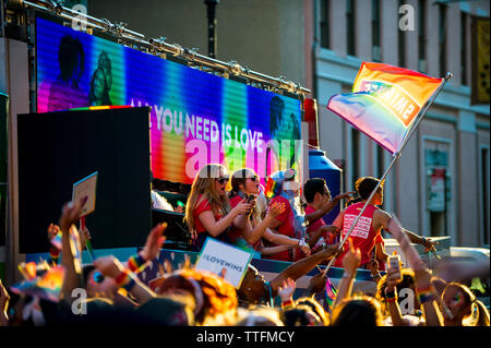 NEW YORK CITY - JUNE 25, 2017: Participants on a float sponsored by the vodka brand Smirnoff wave gay pride rainbow flags at the annual Pride Parade. Stock Photo