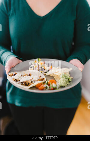 Midsection of woman holding plate with food at home Stock Photo