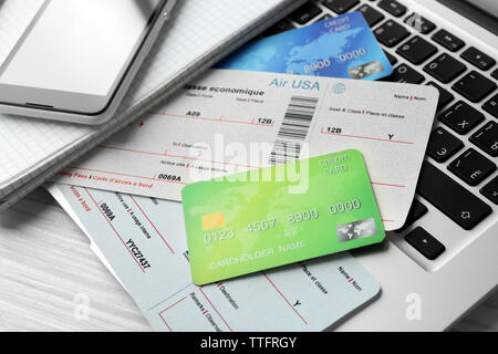 Laptop with mobile phone, credit cards and flight tickets on light wooden table Stock Photo
