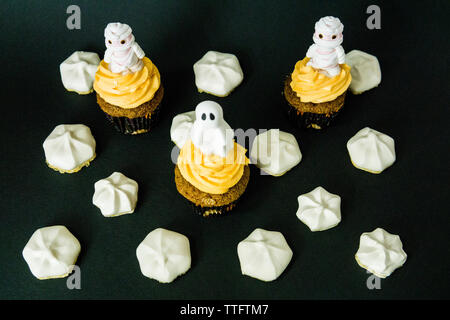 Funny scary cupcakes on a black bacground with meringue all around Stock Photo