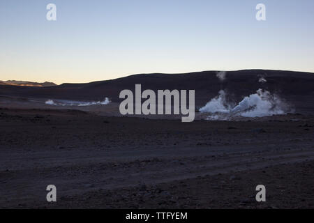 Steam emitting from geyser at Salar De Uyuni against clear sky during dusk Stock Photo