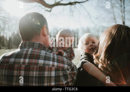 Baby and toddler look over shoulder of their parents.