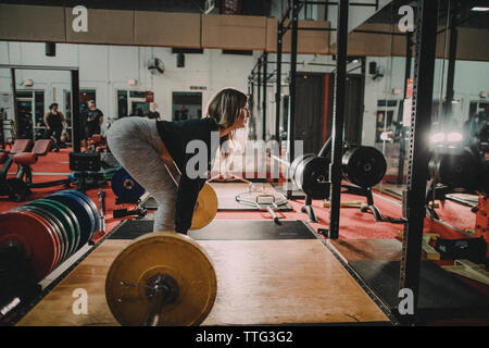 Side view of attractive millennial aged woman training on squat rack Stock Photo