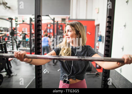 Thoughtful woman leaning on barbell at the gym Stock Photo