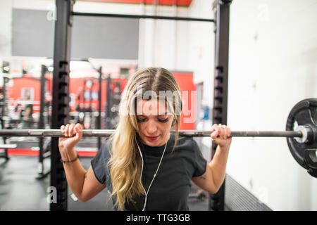 Woman exercising in gym, using barbell Stock Photo