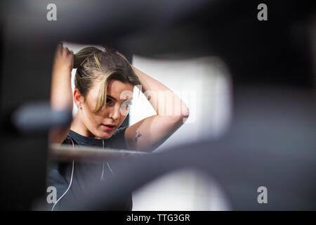 Attractive woman ties her hair up during a workout at the gym. Stock Photo