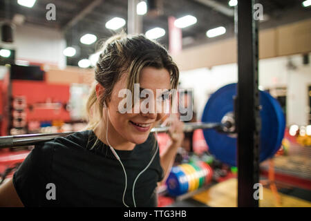 Smiling woman weight lifting with barbell in gym Stock Photo