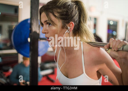 Cropped view of attractive woman lifting barbell in gymnasium Stock Photo