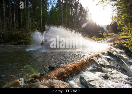 Offroad vehicle driving through river in British Columbia. Stock Photo