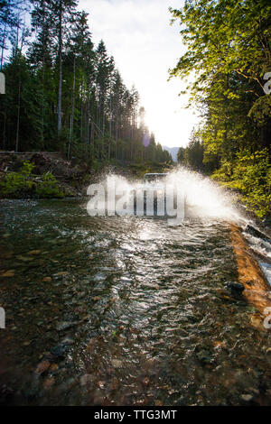 Offroad vehicle driving through river in British Columbia. Stock Photo