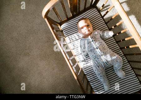 Sunlight and shadows cast on a baby laying in a wooden cradle