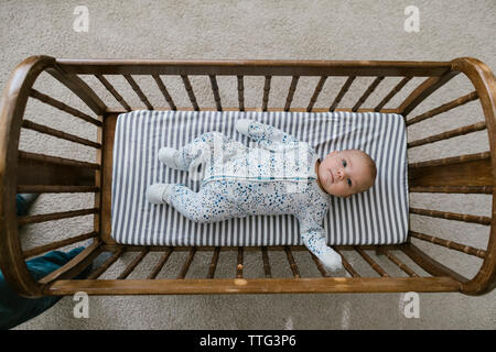 Father looking down on baby laying in crib after nap. Stock Photo