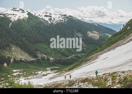 Three mountaineers hike up a vast valley near Squamish, B.C. Stock Photo