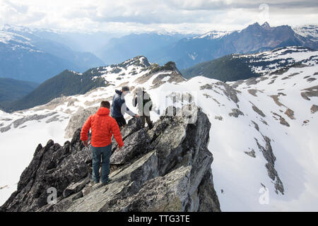Three mountaineers descend from the summit of a mountain. Stock Photo