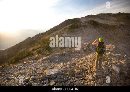 Backpacker blocks the sun with his hand while hiking in the evening. Stock Photo