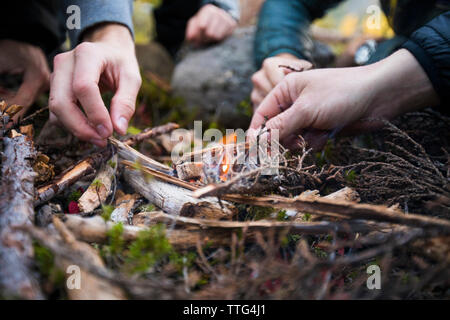 low angle view of many hands working to light a fire outdoors. Stock Photo
