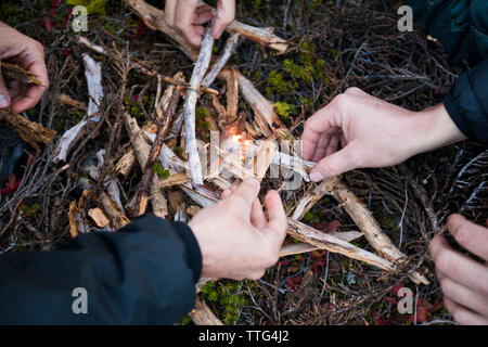 Many hands work to light a fire outdoors. Stock Photo