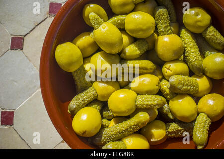 Pickled olives stuffed with gherkins served on clay bowl. Overhead sho Stock Photo