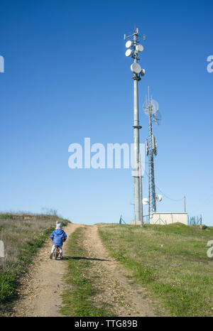 young boy on bike by cell phone tower Stock Photo