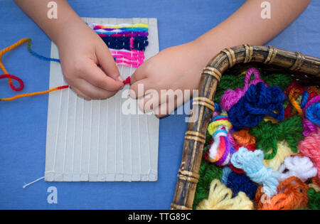 Child girl learning to use cardboard weaving loom Stock Photo