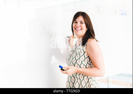 Teacher Smiling and Writing on Whiteboard Stock Photo