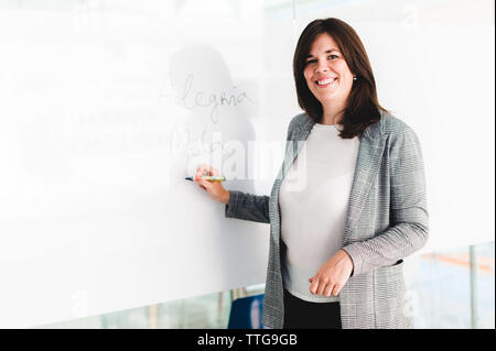 Teacher Smiling and Writing on Whiteboard Stock Photo