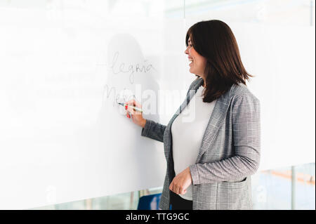 Teacher Smiling and Writing on Whiteboard Stock Photo
