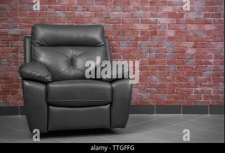 Brown leather armchair against brick wall background Stock Photo