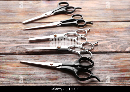 Professional metal scissors lying on wooden table, close up Stock Photo