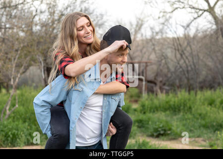 Western wear young couple horsing around on ranch Stock Photo