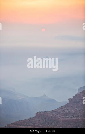 Sun rising through smoke and fog in Grand Canyon Stock Photo