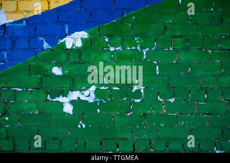 A wall painted in green, blue and yellow with snow on it Stock Photo
