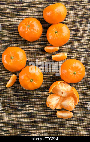 Fresh, delicious tangerines  in different conditions, peeled, unpeeled, sliced on the stripped material, top view Stock Photo