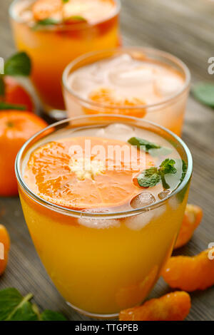 Tangerine cocktails with sliced mandarins, ice, mint on a wooden table, close up Stock Photo