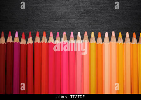 Watercolor pencils lined up on a black table. Stock Photo
