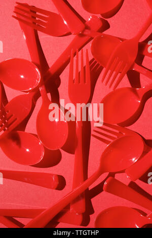 Red disposable plastic cutlery on a red table. Stock Photo