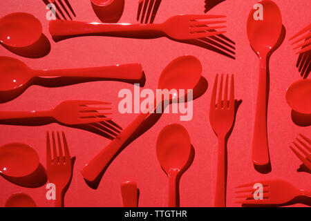 Red disposable plastic cutlery on a red table. Stock Photo