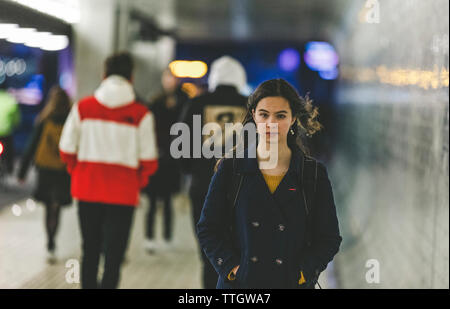 Tired young womanwith backpack is walking on subway station in evening Stock Photo